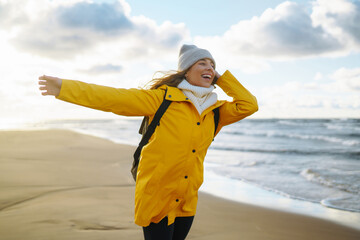 Happy tourist in a yellow jacket standing and looking on sea. Lifestyle, travel, tourism, nature, active life.