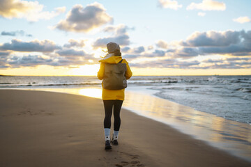 Happy tourist in a yellow jacket standing and looking on sea. Lifestyle, travel, tourism, nature,...