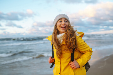 Happy tourist in a yellow jacket standing and looking on sea. Lifestyle, travel, tourism, nature, active life.
