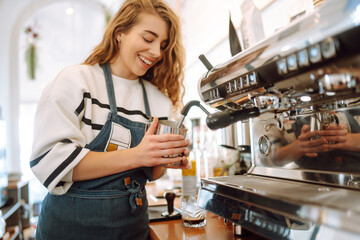 Female barista making coffee in a coffee machine. Food and drink concept.