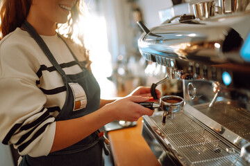 Female barista making coffee in a coffee machine. Food and drink concept.