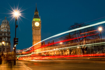 Fototapeta na wymiar A long exposure of traffic trails through Parliament Square in August 2022 as Big Ben towers above the London skyline.