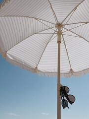 Sunglasses and beach umbrella over blue sky © Floral Deco