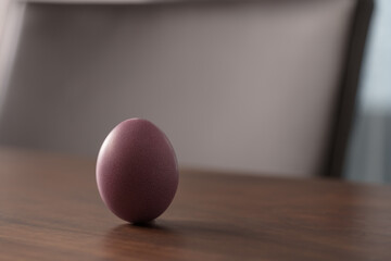 Purple Easter egg on a wooden table with copy space