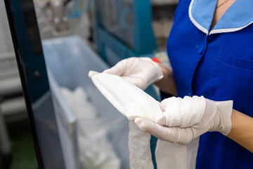A female employee performs visual quality control of hosiery.