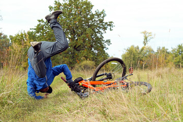Stressed male cyclist falling from a bicycle fter a bad accident. Young man suffering a bike...