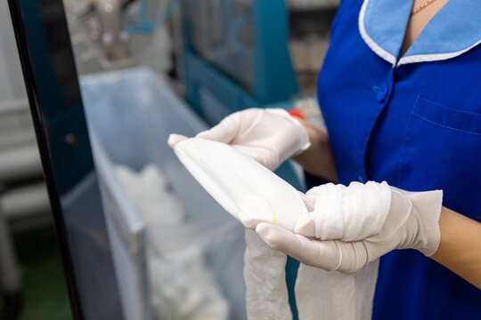 A female employee performs visual quality control of hosiery.