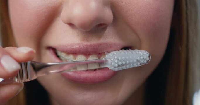 Close Up. Oral hygiene for braces. Teen girl cleaning and brushing teeth with clear ceramic braces using special brushing tools.