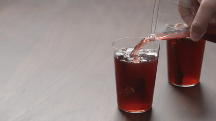 man hand pour mulled wine in thin tumbler glasses on walnut table