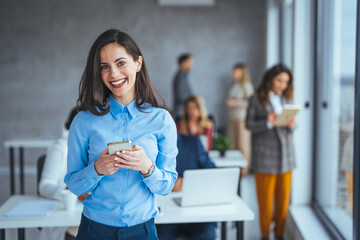 Shot of a young businesswoman using a cellphone in an office. Shot of an attractive young businesswoman using a smartphone in a modern office. Smiling business woman in casuals talking on phone.... - Powered by Adobe