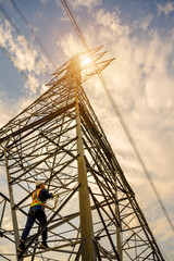 Electric worker climbs pylon to repair electrical system at renewable energy power station at high voltage pylon.