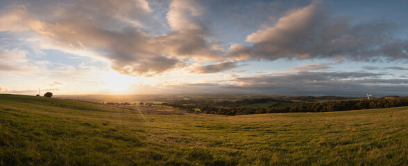Scottish panorama with field and clouds at sunset. The setting sun illuminates the Scottish countryside. West Lothian, Scotland 