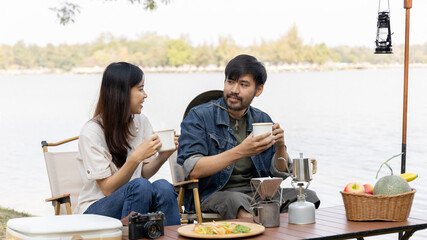 Young couple camping weekend in the woods near river, Enjoying Camping Holiday In Countryside, Leisure activities, Dating and relaxation in nature, Couple dripping coffee and sipping coffee.