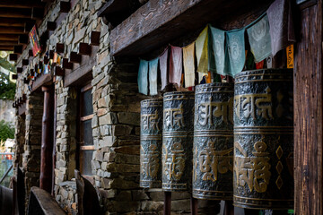A row of metal tibetan buddhist prayer wheels with golden matra letters. 