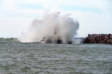 Fototapeta na wymiar Winter storm with big waves crashing in to a beacon