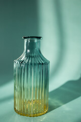A glass bottle is a flower vase. Shadow. Glassware on a turquoise background