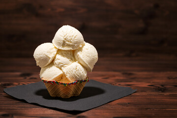 vanilla flavor scoops of ice cream in waffle cup on wooden background, dark style
