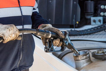 Truck driver with a pump nozzle in his hands filling the vehicle's fuel tank, Close-up.