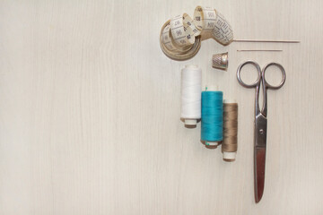 Sewing accessories, threads, needles, scissors, thimble on a white table. Sewing and hobby concept.