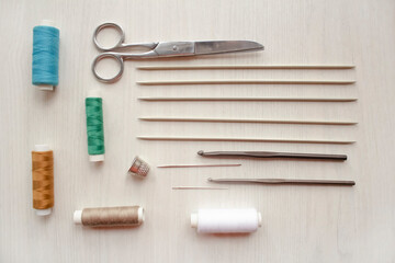 Sewing accessories, threads, needles, scissors, thimble on a white table. Sewing and hobby concept.