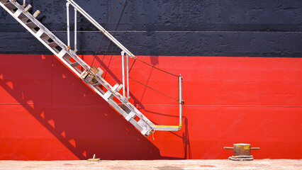 Background of White gangway accommodation ladder of red and black oil tanker while moored at the...