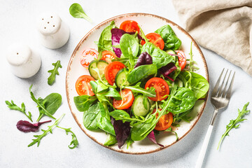 Green salad with fresh leaves and vegetables in white plate. Top view.