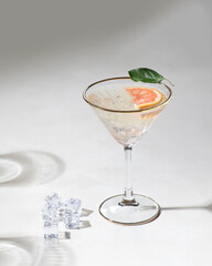 Pink cocktail with mint leaves in glass goblet.