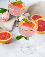 Pink cocktail with mint leaves in glass goblet.
