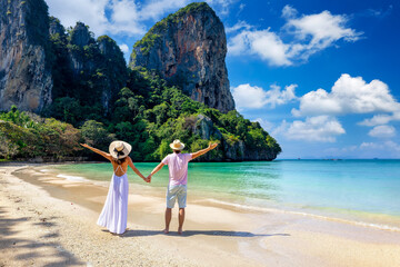 A happy couple stands on the beautiful beach of Railay, Krabi, Thailand, during their summer...