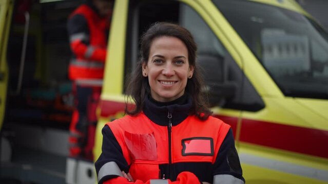 Young woman doctor standing in front of ambulance car.