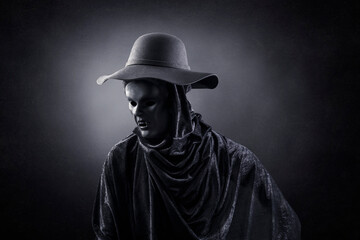 Vampire with old hat over dark misty background