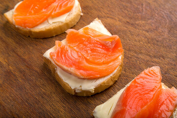 Toasts with trout and butter on a wooden table.