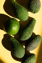 avocado top view. beautifully arranged avocados on a yellow background with a beautiful shadow.
