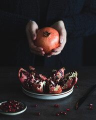 Fresh pomegranate seeds on plate, black background.