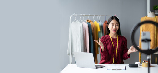 Passionate Asian business owner, dress or cloth online store interacting with her customers online,...
