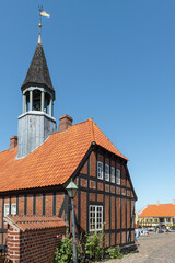 Fototapeta premium Das alte Rathaus von Ebeltoft, Djursland, Dänemark aus Fachwerk, rotem Backstein und mit Turm in der Sonne vor blauem Himmel