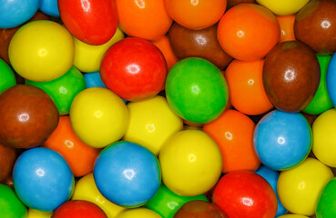 Multi-colored round and oval candies in bulk full depth of field background wallpaper, uniform texture pattern
