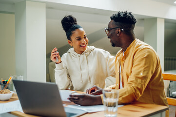 Diverse couple sitting in a home office and holing keys of their new home