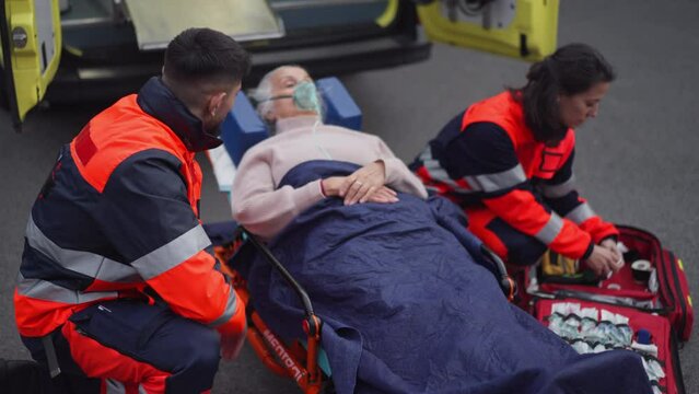Rescuers taking care of patient, preparing her for transport.