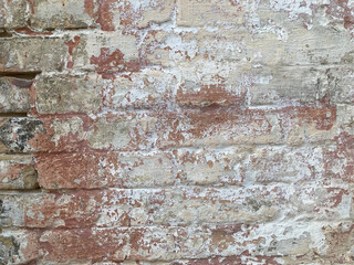Background of old vintage dirty brick wall with peeling plaster, texture. Old multi colored brick...
