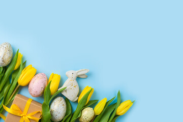 Modern background for Easter holiday with easter golden eggs, gift box and yellow  tulip flowers. Top view, flat lay