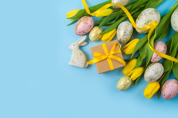 Easter holiday background with easter eggs, gift box and yellow  tulip flowers. Top view, flat lay