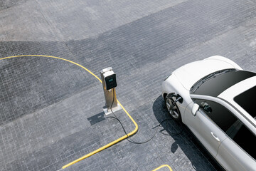 Aerial top view image of progressive green energy-powered charging station, electric vehicle at...