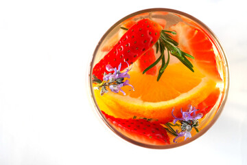 The glass with water flavored with orange, strawberries and rosemary.