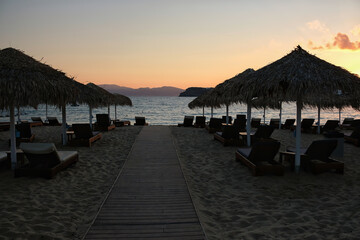 Fototapeta na wymiar View of a wooden path leading to the stunning beach of Mylopotas in Ios Greece at sunset