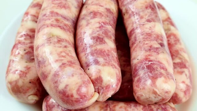 Fresh raw homemade pork sausages for barbecue circle rotation close up