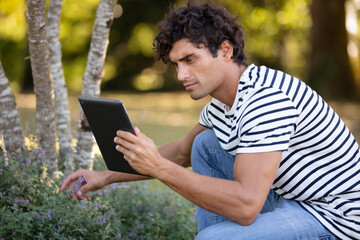 handsome man holding a tablet looking for plant references