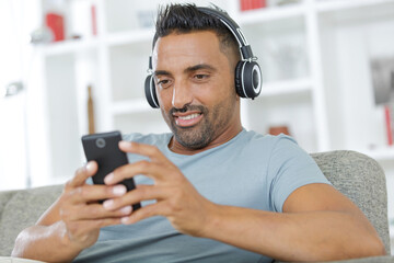 man listening to music with headphone on sofa