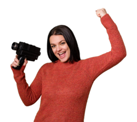 A young woman happily films with an antique video camera on an isolated background. She captures memories, smiling and enthusiastic while recording her story
