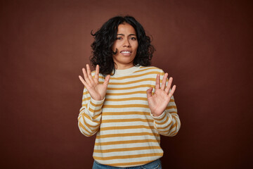 Young colombian curly hair woman isolated on brown background rejecting someone showing a gesture...